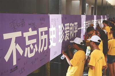 中国侨网图为华裔青少年在“不忘历史 珍爱和平”横幅上签名。新华报业视觉中心记者 万程鹏 实习生 陈俨 摄