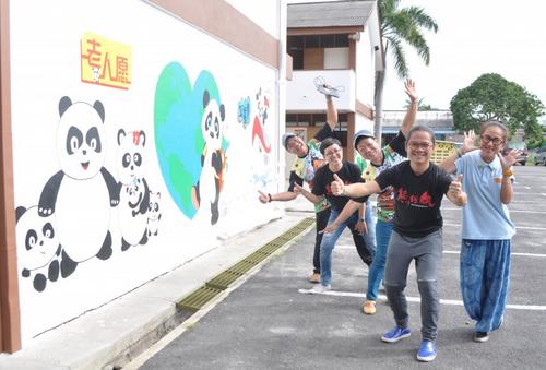 中国侨网熊猫爱心团队成员为农村华小绘制壁画。(马来西亚《星洲日报》)