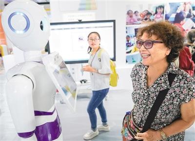 中国侨网在首届中国北京国际语言文化博览会上，一名参观者与智能客服机器人交流。 新华社记者 沈伯韩摄