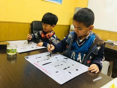 中国侨网西班牙爱华中文学校的学生在练习写书法。（西班牙《欧华报》）