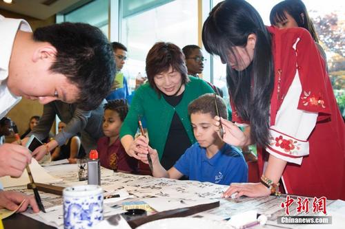 中国侨网当地时间5月3日，2018年“感知中国——美国中小学生走进总领馆”活动在中国驻纽约总领馆举行，中国驻纽约总领事章启月手把手教美国学生握笔写中国书法。此次开放日活动以“感知中国”为主题，通过书法、剪纸、编中国结等体验项目，使参加活动的同学在轻松活泼的游戏氛围中认识中国、了解中国文化、体验中国美食。 中新社记者 廖攀 摄