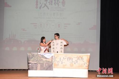 中国侨网当地时间5月6日，第十七届“汉语桥”世界大学生中文比赛巴西大区赛决赛，在巴西南大河州阿雷格里港市南大河州联邦大学举行。此次比赛由中国国家汉办主办，中国驻巴西大使馆文化处承办，巴西南大河州联邦大学孔子学院协办。来自巴西全国10所孔子学院的17名选手参赛。图为参赛选手进行中国书法表演。中新社记者 莫成雄 摄