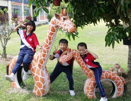 中国侨网长颈鹿模型是小学生蹦蹦跳跳玩耍好去处。（马来西亚《星洲日报》）