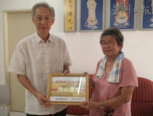 中国侨网童星存(左)代表宽柔中学,赠送感谢状予彭金梅。(图片来源:马来西亚《星洲日报》)