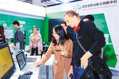 中国侨网第二届中国北京国际语言文化博览会上,“面向智能语音教学的汉语中介语语音多模态语料库研究”项目组成员冯晓莉(左)在介绍新推出的汉语学习客户端。 冯晓莉供图