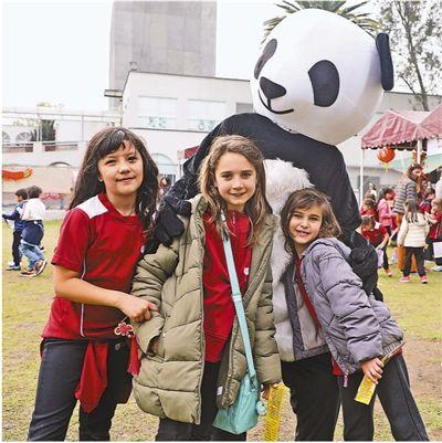 中国侨网1月24日,在墨西哥城孔子学院举办的春节活动上,3个小朋友和1名学生家长扮演的大熊猫合影。 本报记者 刘旭霞摄