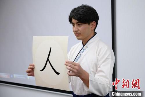 中国侨网来自阿富汗的新生代表李伟在老师指导下用毛笔写下“人”字。　韦亮　摄
