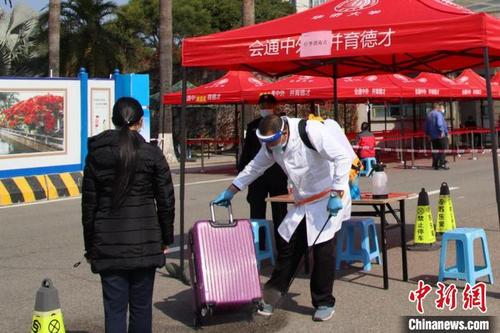 中国侨网2月16日起,华侨大学学生错峰返校。图为工作人员在为学生行李消杀。 华侨大学供图