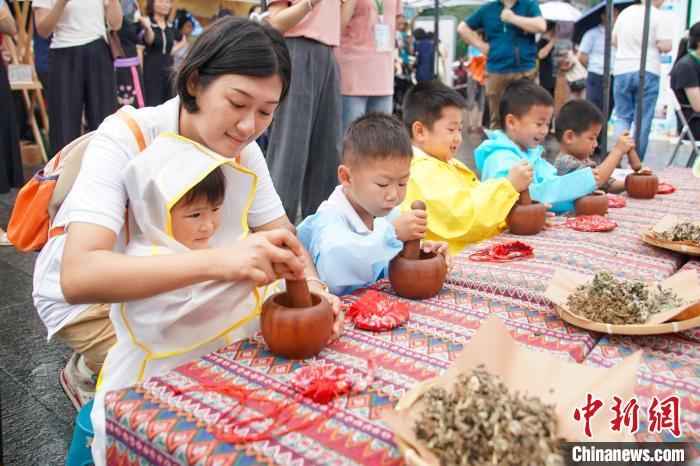 中国侨网6月14日,广西南宁,儿童在中医药文化市集上体验制作中药驱蚊香囊。广西中医药文化服务月暨文化市集活动周主场活动当日在南宁“三街两巷”启动,现场举办中医药文艺表演、中医药文化市集等活动,民众可体验到中医药健康义诊、品尝中药(壮瑶药)药膳等。中新社记者 陈冠言 摄