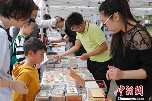 中国侨网资料图：“世界读书日”民众在上海徐汇滨江感受都市阅读文化. 家长带着孩子在现场挑选自己喜爱的书籍。　殷立勤 摄