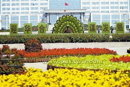 中国侨网10月14日,两位市民从立体花坛旁走过。第五届“华合论坛”即将召开,(平顶山)市园林处在新城区平安广场制作了立体花坛“孔雀开屏”,热情欢迎参加论坛的华侨华人代表。 (平顶山新闻网/李志勇 摄)