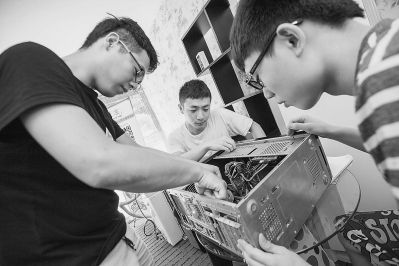 林芝呈和合作伙伴正在检查一台刚刚回收来的二手电脑主机。（《福建日报》/林双伟
