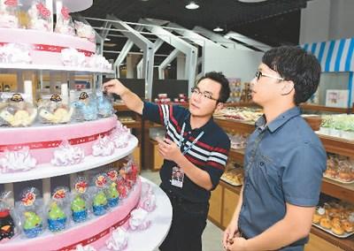 中国侨网台湾青年创业者曾翊展（左）在厦门“宝岛梦工厂”里指导员工摆设商品。 新华社记者 姜克红摄