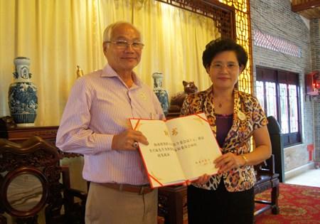 中国侨网资料图：图为印尼海南总会名誉主席李兴福先生(左)获颁顾问证书。（图片来源：南海网）