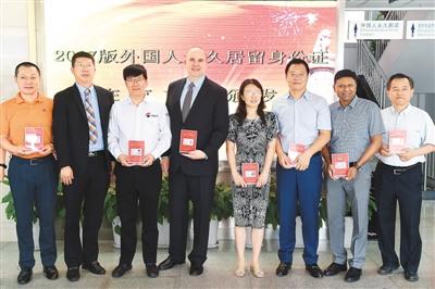 中国侨网6月16日,在北京市公安局出入境管理局中关村外国人服务大厅,首批获得2017版外国人永久居留身份证的外籍人士合影。 新华社记者 鞠焕宗摄