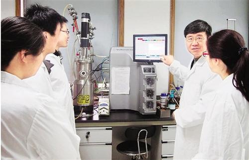中国侨网王一成(右二)生前给省农科院的学生讲解发酵罐使用方法。
