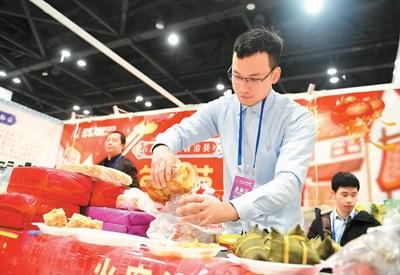 中国侨网广西电商年货节日前在南宁举行。图为一名参展商准备将产品给顾客品尝。 　新华社记者 陆波岸摄