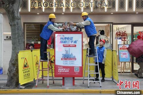 中国侨网中国电信的工作人员正在电话亭的顶盖内安装调试5G微基站。 张亨伟 摄
