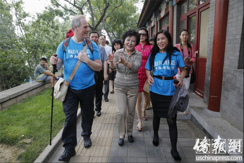 中国侨网7月27日，裘援平(中)在北京街头为麦克·贝茨勋爵夫妇介绍京城文化。(美国侨报 王泽 摄)