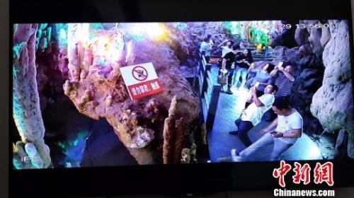 中国侨网图为一游客在景区游玩时用力踢石钟乳。景区监控视频截图。