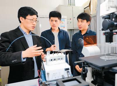 中国侨网2017年3月28日，泰国留学生卡纳特（右）和同学在西安交通大学机械工程学院教授韦学勇（左）指导下进行生物微流控芯片研究。 　　新华社记者 李一博摄