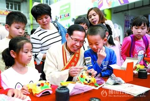 中国侨网佛山市第三届争做“佛山小当家”活动现场,国家级非遗项目彩扎(佛山狮头)传承人黎伟指导小选手们进行狮头扎作。/佛山日报记者甘建华摄