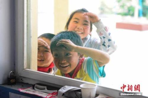 中国侨网资料图：儿童节，3名学生与老师玩捉迷藏游戏，偷看老师行踪。中新社记者 张勇 摄