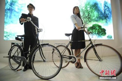 中国侨网资料图:模特展示复刻版的新中国第一辆国产“飞鸽1950”自行车(左一),它的旁边,则是1989年作为“国礼”送给时任美国总统老布什访华礼物的复刻车(右一)。中新社发 佟郁 摄