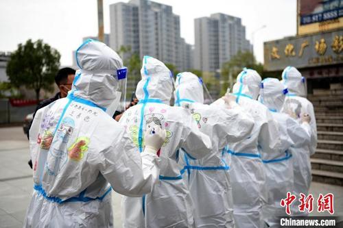 中国侨网在江西省上饶市铅山县河口镇文化广场，做完核酸检测的医护人员正在防护服上画上各种各样的美图。　丁铭华　摄