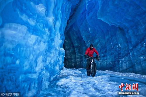 男子骑车横跨穿越30米高蓝色冰洞