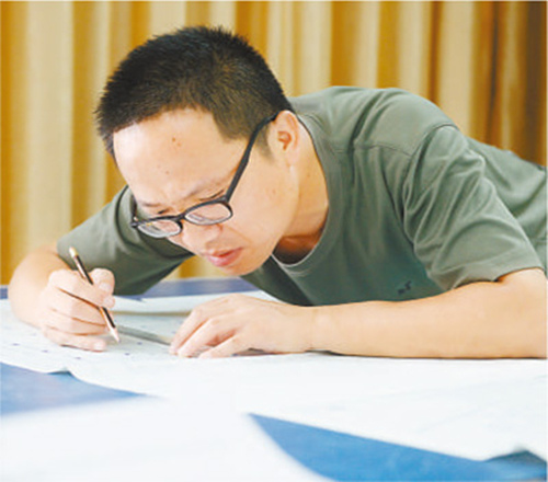 周湘虎正在核对修改施工图纸。