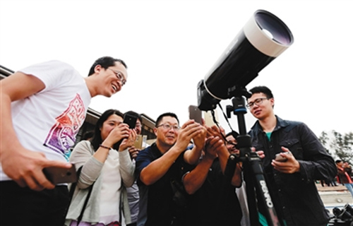 长征五号发射前，观众们被一名摄影爱好者的望远镜吸引，好奇地对着相机显示屏上的画面进行翻拍。