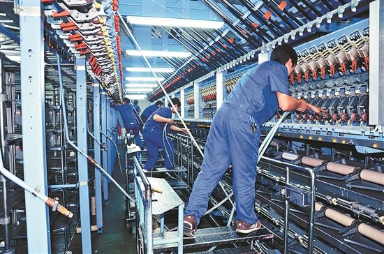机器换人提高纺织生产效率。图为工人在自动生产线上操作。