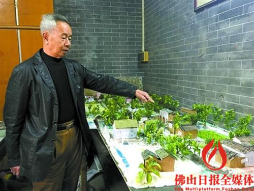 中国侨网陈顺荣介绍自制的沙盘模型，展示古村落建筑群。 