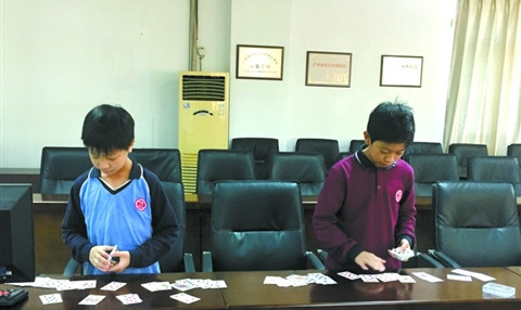 中国侨网招一天(右)和“小师弟”演示快速扑克牌记忆,37秒内便背下一副乱序扑克牌,并在1分钟内准确无误地排出所有牌面。