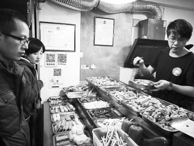 中国侨网柯武义(右)在店里忙着给顾客打包。