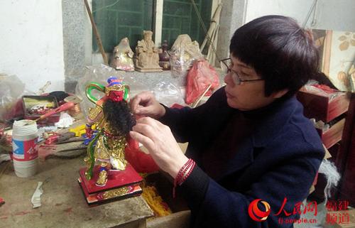 中国侨网洪碧虹正在为即将完工的佛像栽胡须。
