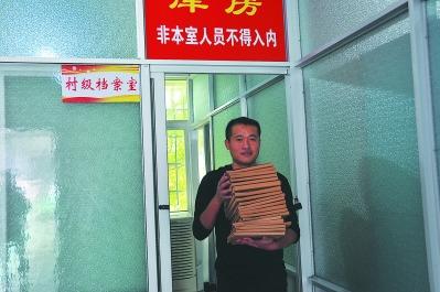 中国侨网城厢区华亭镇综合档案室负责人为申请查询的群众查找档案材料。