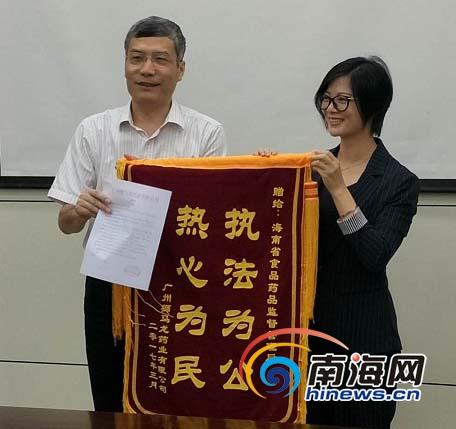 中国侨网企业代表(右)将锦旗交到海南省食药监管局副局长贾宁手上。南海网记者姜飞摄