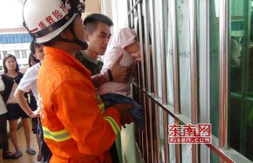 中国侨网5岁小女孩头卡窗户栅栏。