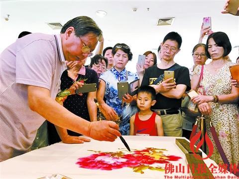 中国侨网国画名家陈永康现场画牡丹，引市民围观。