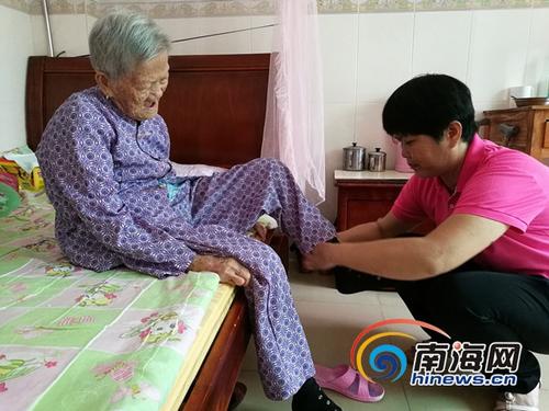 中国侨网韩文英给光荣院里的老人穿袜子。南海网记者高鹏 摄