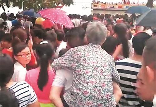 中国侨网在拥挤的人群中，李军背着母亲成了最美的背影。 (视频截图)