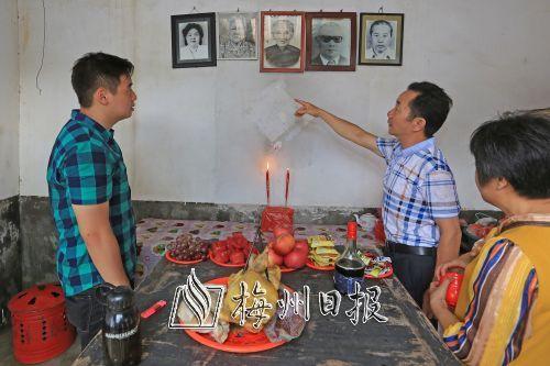中国侨网丘震伟（左一）的伯父向他介绍老屋内的祖先相片。（高讯 摄）