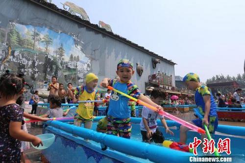 中国侨网第三届呀路古泼水狂欢季今天在北京呀路古热带植物园开幕。图为孩子们在泼水节中享受夏日清凉。　陈明　摄
