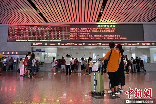 中国侨网8月23日，广西南宁东站售票大厅内，两名旅客驻足观看列车停运信息。 中新社记者 俞靖 摄