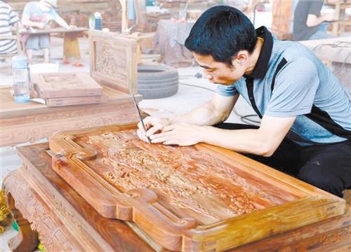 中国侨网李炳祺手工修磨家具上的图案。陈英 摄