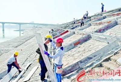 中国侨网在南堤整治工程施工现场,施工人员正在迎水坡用混凝土浇筑格构梁。 本报记者 黄春生 摄