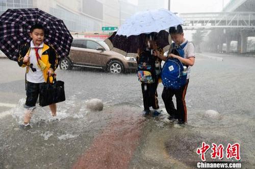 中国侨网图为小学生涉水通过。　洪坚鹏　摄