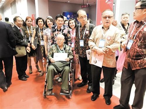 中国侨网祖籍新会的印尼华人容启耀坐着轮椅参加世广会。